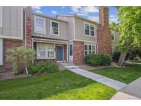 Charming townhouse featuring brick accents, a well-manicured lawn, and a welcoming blue front door at 9679 W Chatfield Ave # C, Littleton, CO 80128