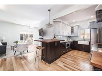 Modern kitchen featuring an island with seating, stainless steel appliances, and wood floors at 4729 W 32Nd Ave, Denver, CO 80212