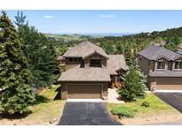 Well-maintained exterior elevation with a two-car garage, mature landscaping, and a mountain view in the background at 24045 High Meadow Dr, Golden, CO 80401
