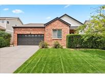 Charming brick home featuring a well-manicured lawn and attached two-car garage at 13983 E 104Th Pl, Commerce City, CO 80022