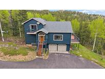 Two-story home with a wooden porch, two car garage and forest in the background at 11222 Conifer Mountain Rd, Conifer, CO 80433
