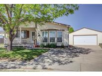 Inviting single-story home with a well-manicured front yard, long driveway, and detached garage at 233 Cherokee Ct, Brighton, CO 80603
