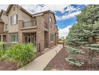 Charming two-story townhouse with brick facade, balcony, and beautifully landscaped walkway at 606 E Dry Creek Pl, Littleton, CO 80122