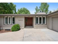 Charming ranch-style home features a brick facade, wood door, manicured landscaping, and an inviting entryway at 5653 E Southmoor Cir, Englewood, CO 80111