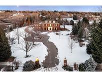 Brick colonial home on a large lot with a long driveway, snow covered landscape, and beautiful landscaping at 5700 S Steele St, Greenwood Village, CO 80121
