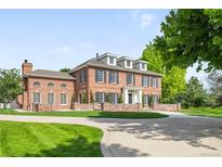 Stately brick home featuring a circle driveway, well-manicured lawn, and classic architectural design at 5700 S Steele St, Greenwood Village, CO 80121