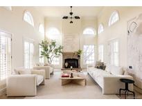 Bright living room featuring high ceilings, arched windows, a stone fireplace, and stylish neutral decor at 5700 S Steele St, Greenwood Village, CO 80121