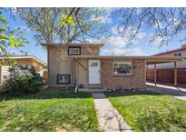 Charming front exterior featuring a walkway, well-maintained lawn, and a combination of brick and siding at 6690 Albion St, Commerce City, CO 80022