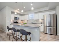 Modern kitchen with stainless steel appliances, white cabinets, a gray countertop island, and pendant lighting at 28418 E 8Th Pl, Watkins, CO 80137