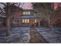 Charming two-story red brick home with walkway dusted with snow leading to the front door at twilight at 2038 S Columbine St, Denver, CO 80210