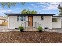 Charming single story home featuring a white painted brick exterior and a cozy front porch with black metal railings at 5573 S Huron St, Littleton, CO 80120
