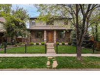 Charming two-story home with stone accents, manicured lawn, and decorative black metal fence at 1927 S Grant St, Denver, CO 80210