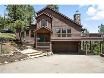 Charming brown two-story home with stone accents, a covered porch, and a two-car garage at 7221 S Brook Forest Rd, Evergreen, CO 80439