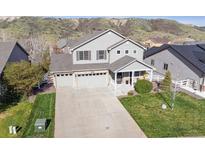 Two-story home featuring a three-car garage, a welcoming front porch, and well-manicured lawn at 3978 Aspen Hollow Ct, Castle Rock, CO 80104