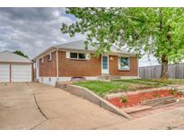 Charming brick home with a detached garage and landscaping in front at 10420 Marion St, Northglenn, CO 80233