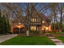 Charming Tudor-style home featuring a brick facade, arched doorways, a well-manicured lawn, and an attached two-car garage at 10 Cherry St, Denver, CO 80220