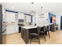 Modern kitchen features white cabinets, a dark island with seating, and updated appliances at 3924 Alamosa Ct, Brighton, CO 80601