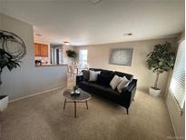 Comfortable living room with neutral carpet, modern sofa, and easy access to adjacent dining area at 1496 S Pierson St # 116, Denver, CO 80232