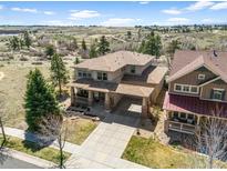 Beautiful two-story home with a covered side-entry carport and mature landscaping surrounded by green spaces at 12119 S Wanderlust Way, Parker, CO 80138