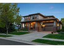 Charming two-story home featuring an inviting front porch and attached garage with manicured lawn, perfect for Gathering living at 12119 S Wanderlust Way, Parker, CO 80138