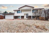 Split-level home featuring a white facade, brick accents, a two-car garage, and low-maintenance landscaping at 301 S Troy St, Aurora, CO 80012