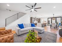 Bright living room featuring a modern sectional sofa, open staircase, and seamless flow into the kitchen area at 3928 Vrain St, Denver, CO 80212