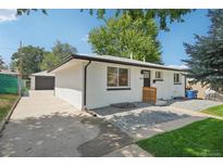 Ranch style home with white brick exterior, landscaped lawn, and a modern front door at 3781 S Hooker St, Englewood, CO 80110