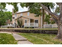 Charming exterior view of a townhouse with a white picket fence and stone chimney, situated in a suburban neighborhood at 8463 Everett Way # B, Arvada, CO 80005