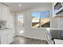 Well-lit kitchen with white cabinets, modern appliances, and a large window offering a pleasant view at 4835 Grove St, Denver, CO 80221