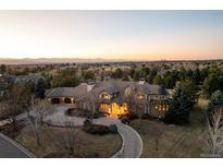 Stunning aerial view of a luxury home with a circular driveway and a scenic mountain backdrop at sunset at 4041 E Forbes Ct, Greenwood Village, CO 80121
