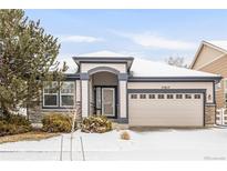 Charming single-story home featuring stone accents, a two-car garage, and a well-maintained front yard with winter snow at 23612 E Mississippi Cir, Aurora, CO 80018