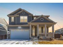 Two-story house with gray siding, white garage door, and a covered porch at 12224 Olive Way, Thornton, CO 80602