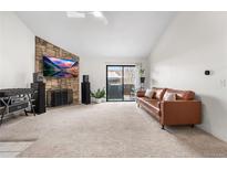 Spacious living room features a stone fireplace, large TV, and sliding glass door to balcony at 3305 S Ammons St # 202, Lakewood, CO 80227