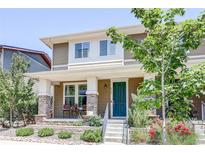 Charming townhome featuring a covered porch, brick accents, and freshly landscaped front yard at 8321 E 33Rd Ave, Denver, CO 80238