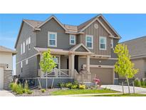 Charming two-story home featuring a welcoming front porch and attached garage, set against a clear blue sky at 864 Clover Loop, Erie, CO 80026