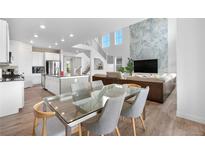Bright, open living space featuring a modern kitchen, dining area, and living room with a striking accent wall at 864 Clover Loop, Erie, CO 80026