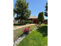 Charming home with lovely landscaping, beautiful flowers, mature trees, and a red garage door at 460 Yates St, Denver, CO 80204