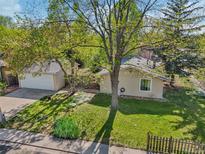 Charming home exterior featuring mature trees, green lawn, and detached garage at 943 Pinon Ct, Longmont, CO 80504