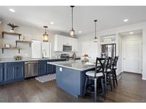 Modern kitchen with dark blue cabinets, stainless steel appliances, and a spacious island with seating at 18079 E 108Th Pl, Commerce City, CO 80022