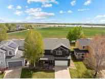 Aerial view of a two-story home in a neighborhood with a large grass field in the background at 5249 Mt Arapaho Cir, Frederick, CO 80504