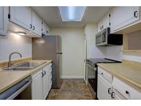 Galley kitchen with stainless steel appliances, white cabinets, and a skylight providing natural light at 3494 S Eagle St # 202, Aurora, CO 80014