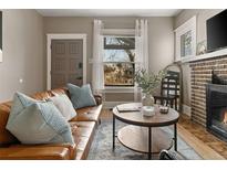 Comfortable living room with a leather sofa, brick fireplace and a bright window at 3725 Federal Blvd, Denver, CO 80211