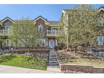 Inviting two-story townhome featuring manicured landscaping and a charming brick facade on a sunny day at 9182 Ridgegate Pkwy, Lone Tree, CO 80124