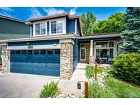 Charming two-story home featuring a blue exterior, stone accents, well-manicured landscaping, and an attached two-car garage at 1941 Fox Fire St, Highlands Ranch, CO 80129