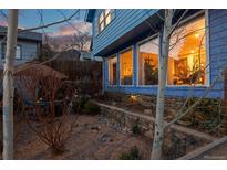 Charming blue home featuring large windows and a stone retaining wall, set against a colorful twilight sky at 2041 Virginia St, Idaho Springs, CO 80452