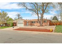 Charming single-story brick home with a manicured front yard and attached garage on a sunny day at 8487 W 62Nd Pl, Arvada, CO 80004