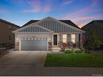 Charming home featuring a well-manicured lawn, gray siding, stone accents, and a cozy front porch at 14066 Ivanhoe Ct, Thornton, CO 80602