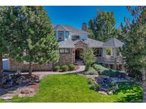 Charming stone and stucco home with lush landscaping, mature trees, and inviting water feature at 5275 Pinyon Jay Rd, Parker, CO 80134