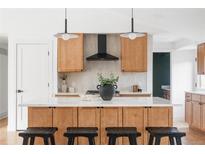 Bright kitchen features a large island with a white countertop, wooden cabinets, and modern light fixtures at 3860 S Spruce St, Denver, CO 80237