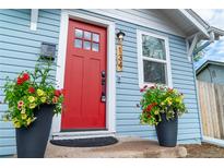 Inviting home entrance with a vibrant red door, lovely potted flowers, and charming exterior details at 134 S Quitman St, Denver, CO 80219